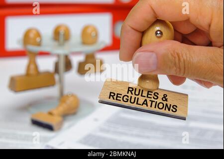 Norme e regolamenti stampati sul timbro di gomma in mano Foto Stock