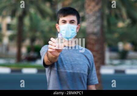 Uomo che tiene igienizzante mani come una precauzione 19 e disinfezione covid all'aperto Foto Stock