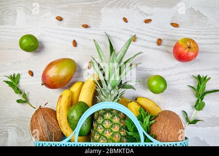 Borsa della spesa della drogheria con frutta esotica biologica su sfondo bianco. Piatto di varietà di frutta tropicale fresca che si spillano da una borsa riutilizzabile Foto Stock