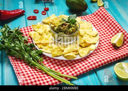 Nachos. Tortilla chips con Guacamole su sfondo di legno blu. Foto Stock