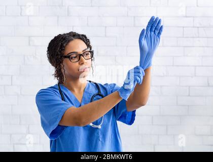 Donna African American veterinario medico mettere su guanti di gomma in ospedale animale, spazio vuoto Foto Stock