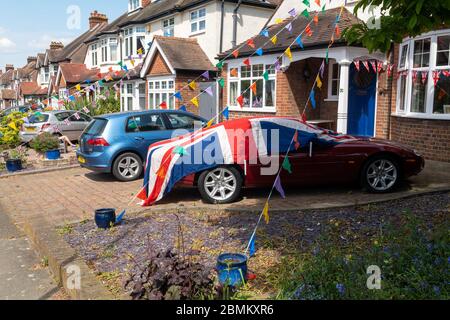 Una strada in una Londra del Sud Ovest vestita di conchigli e una grande bandiera dell'Unione drappeggiata su un'auto Jaguar che celebra il VE Day. Foto Stock