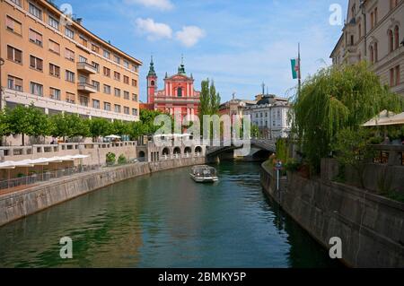 Fiume Lubibljanica con barca turistica vicino al ponte triplo (Tromostovje) e la chiesa francescana, Lubiana, Slovenia Foto Stock