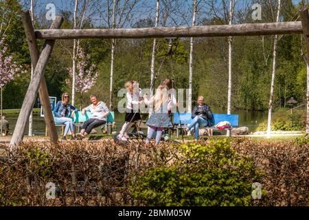 Randers, Danimarca - 09 Maj 2020: Il Parco del Dottore a Randers. I bambini giocano nel parco giochi. Le madri che guardano i bambini giocano su un'altalena. Foto Stock