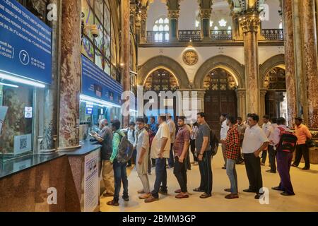 Pendolari al Chhatrapati Shivaji Maharaj Terminus, la stazione ferroviaria più trafficata di Mumbai, India, e un edificio patrimonio dell'umanità dell'UNESCO, in coda per i biglietti Foto Stock