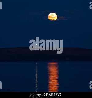 Luna piena che sorge dietro il faro di Copinsay, Orkney Isles Foto Stock