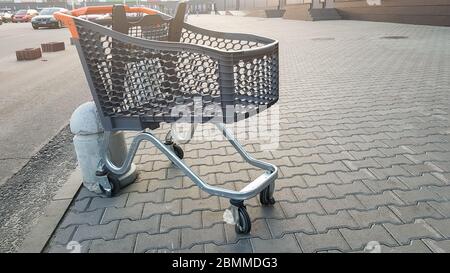 Carrello vuoto all'aperto vicino al supermercato. Solitudine, isolamento carrello, quarantena, coronavirus. Un cestello di plastica vuoto su ruote con p giallo Foto Stock