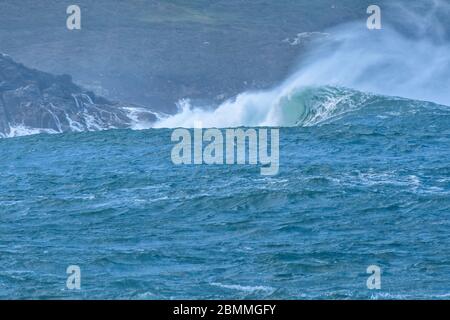 Le onde grandi colpiscono le rocce in mare mosso. In una giornata nuvolosa. Galizia Spagna. Foto Stock