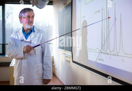 Senior professore di chimica dando una lezione nella parte anteriore dell'aula piena di studenti (SHALLOW DOF; dai toni di colore immagine) Foto Stock
