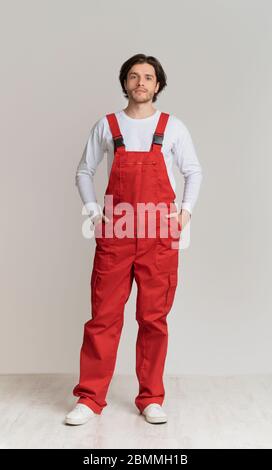 Ritratto di giovane uomo che indossa abiti da lavoro in posa su sfondo chiaro Foto Stock