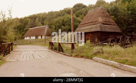 Strada asfaltata con un piccolo ponte in legno e villaggio. Foto Stock