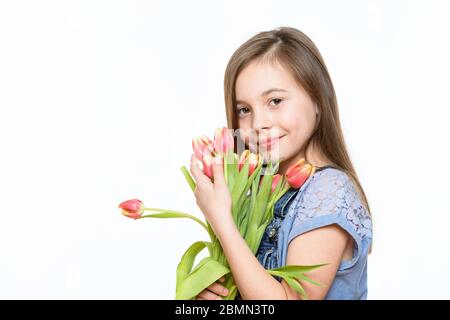 Adorabile bambina con bel sorriso che tiene bouquet di tulipani rosa su sfondo bianco. Felice Festa della Madre, giorno della Donna, giorno del Padre o Bi Foto Stock