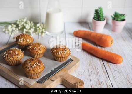 Freschi e deliziosi muffin di carote fatti in casa, decorati con fiocchi d'avena e zucchero di canna su un tavolo rustico. Foto Stock