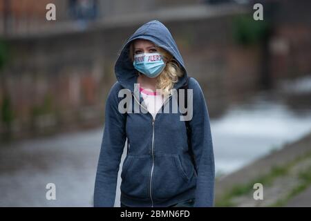 Manchester, Regno Unito. 10 maggio 2020. Una ragazza che cammina vicino al canale Rochdale di Ancoats, Manchester, indossando una maschera facciale con le parole 'Stayin' Alert' su di esso in inchiostro rosso Domenica 10 maggio 2020. (Credit: Pat Scaasi | MI News) Credit: MI News & Sport /Alamy Live News Foto Stock