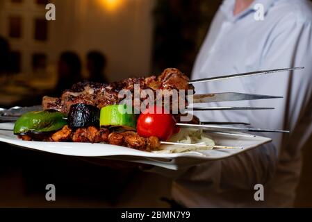 il cameriere tiene un piatto con barbecue in ristorante Foto Stock
