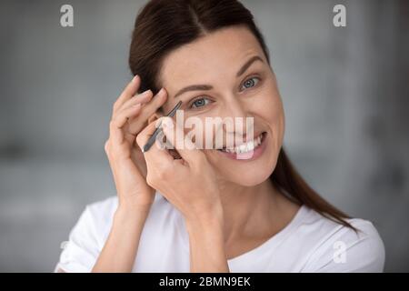 Primo piano ritratto giovane donna adulto tenendo pinzette puck sopracciglia Foto Stock