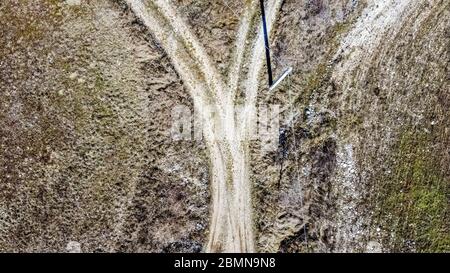 Veduta aerea di un crocevia tra due strade sterrate in aperta campagna. Un palo delinea una lunga ombra sul terreno. Foto Stock