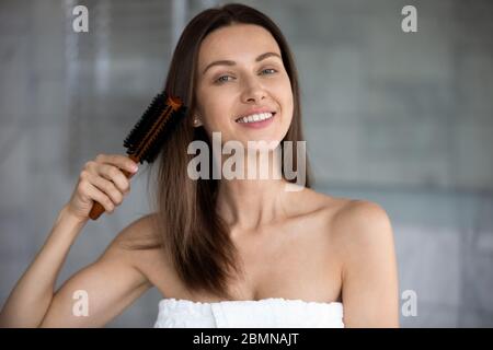 Donna dopo la doccia pettinando i suoi capelli marroni sani Foto Stock