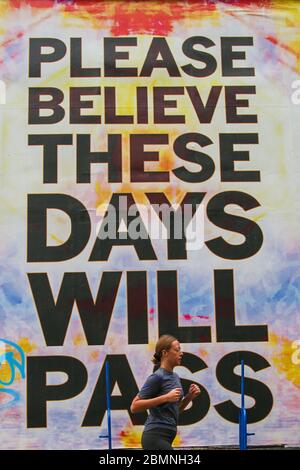 Londra, Regno Unito. 10 maggio 2020. Una donna prende il segno di un poster di Mark Titchner "Please Believe These Days Will Pass" a Londra. Credit: Steve Taylor/SOPA Images/ZUMA Wire/Alamy Live News Foto Stock