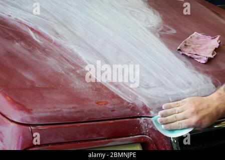 Una vista ravvicinata della mano di un uomo levigando il cofano di un camion prima di un lavoro di verniciatura Foto Stock