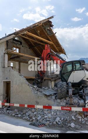 casa abbandonata demolita con escavatore mobile da passeggio e macerie e rocce in primo piano Foto Stock