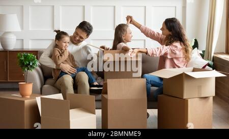Genitori felici che giocano con i bambini il giorno in movimento, disimballaggio scatole Foto Stock