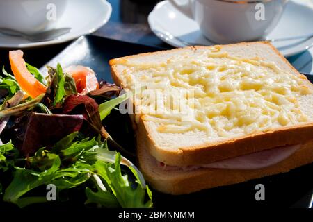 Croque Monsieur un tradizionale panino francese al formaggio Gruyere tostato e prosciutto condito con salsa di bechamel e tagliato a metà Foto Stock