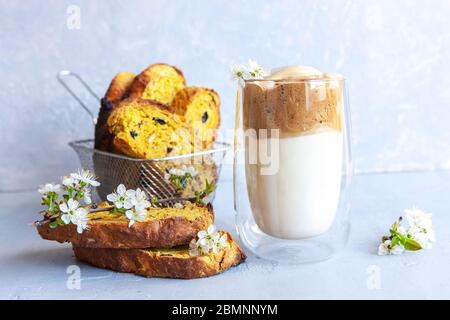 Tazza di caffè alla moda con crema montata e delgona e biscotti italiani su sfondo grigio chiaro. Foto Stock