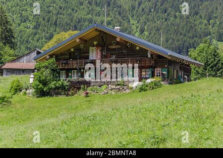 Classico chalet svizzero nel mezzo di verdi prati alpini . Accogliente villaggio rurale Champery in Svizzera. Le pendici delle montagne circostanti sono c Foto Stock