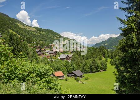 Classico chalet svizzero nel mezzo di verdi prati alpini . Accogliente villaggio rurale Champery in Svizzera. Cielo blu brillante e nuvole bianche e morbide Foto Stock