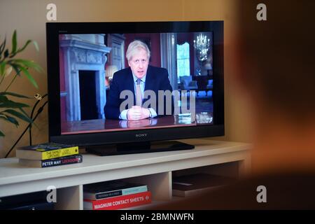 Persone a Wandsworth, Londra guardando il primo Ministro Boris Johnson parlare della nazione sul coronavirus (COVID-19) da 10 Downing Street, Londra. Foto Stock