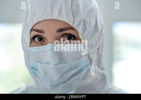 Primo piano di un medico femminile in indumenti protettivi e maschera medica Foto Stock