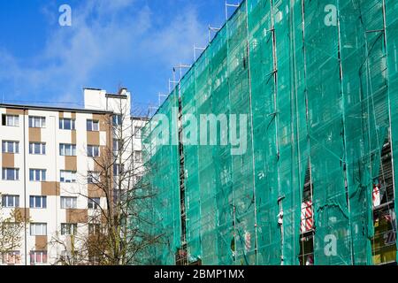 rete di sicurezza verde su impalcature alla facciata di una casa di appartamenti Foto Stock