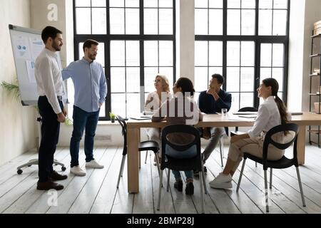 Uomo d'affari per conto dell'azienda che accoglie giovani lavoratori di sesso maschile. Foto Stock