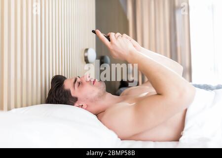 l'uomo usa lo smartphone fin dalla mattina presto. tutto il mondo al telefono. sta blogging. flirtare e inviare messaggi di testo. dipendenza da internet e abus mobile Foto Stock