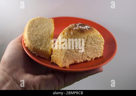 Servire su piatto rosso cheesecake fatto in casa, porzione di servire su piatto rosso da fiocchi di cocco, su sfondo bianco (fuoco selettivo; primo piano) Foto Stock