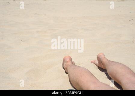uomo, riposo, spiaggia, gambe dell'uomo si trovano sulla spiaggia Foto Stock