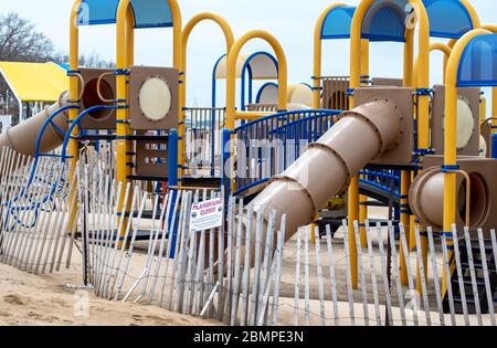 Un'area giochi è vuota sulle rive del lago Michigan, con una recinzione che lo chiude e un cartello chiuso per il parco giochi. Tutti i limiti durante il soggiorno a casa o. Foto Stock