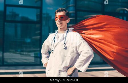 Medico serio in un capo supereroe in piedi su una strada della città Foto Stock