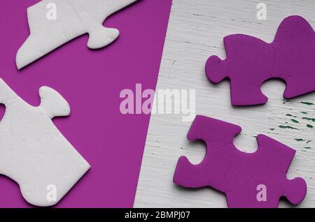 Frammenti del puzzle su uno sfondo lilla. Puzzle bianco e blu non assemblati. Salute psicologica e pensiero logico. Vista dall'alto. Foto Stock