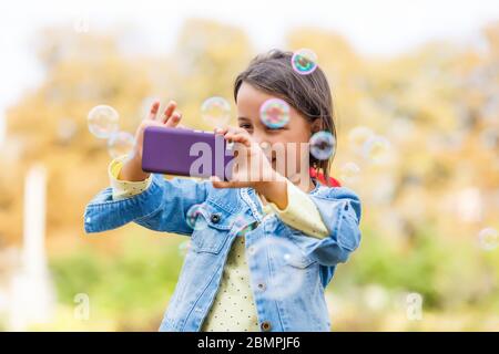 Streaming video. Adorabile bambino che impara nuova tecnologia. Bambina che usa il telefono cellulare. Bambina piccola con smartphone. Telefono cellulare carino Foto Stock