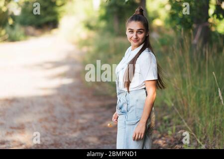 Ragazza in tuta denim sorridente, in natura. Foto Stock