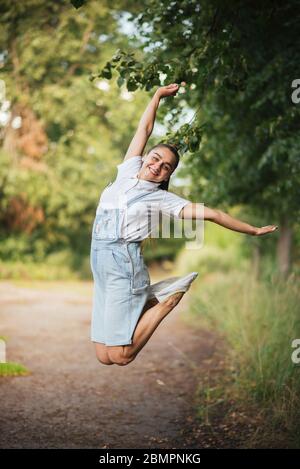 La ragazza in tuta salta con le gambe incrociate. Foto Stock