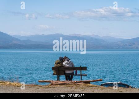 Coppia seduta su panchina dal General Carrera Lake vicino Puerto Rio Tranquilo in Cile, Patagonia, Sud America. Foto Stock