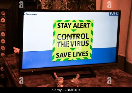 AdviceIl nuovo slogan di informazione pubblica di covid-19 - 'allarme di giorno, controllo del virus, salvare vite ' in televisione. Foto Stock