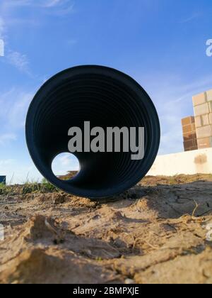 Tubo corrugato di drenaggio in plastica PVC nero forato per la canalizzazione dell'acqua Foto Stock