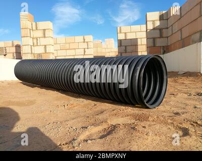 Tubo corrugato di drenaggio in plastica PVC nero forato per la canalizzazione dell'acqua Foto Stock