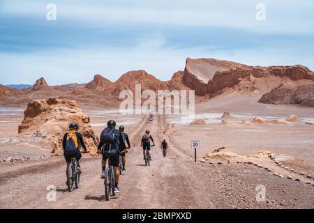 Gruppo di ciclisti che esplorano la Valle della Luna (in spagnolo: Valle de la Luna) nel deserto di Atacama, nel Cile settentrionale, in Sud America. Foto Stock