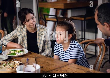 Una famiglia di tre persone che si divertono in un caffè Foto Stock