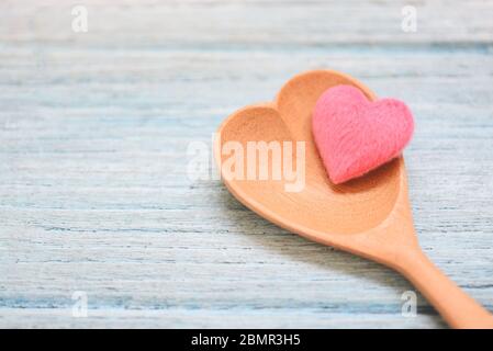 Cuore rosa su cucchiaio di legno e sullo sfondo del tavolo di legno, vista dall'alto / caffè cucchiaio forma del cuore, Love salute o amore concetto di cucina Foto Stock